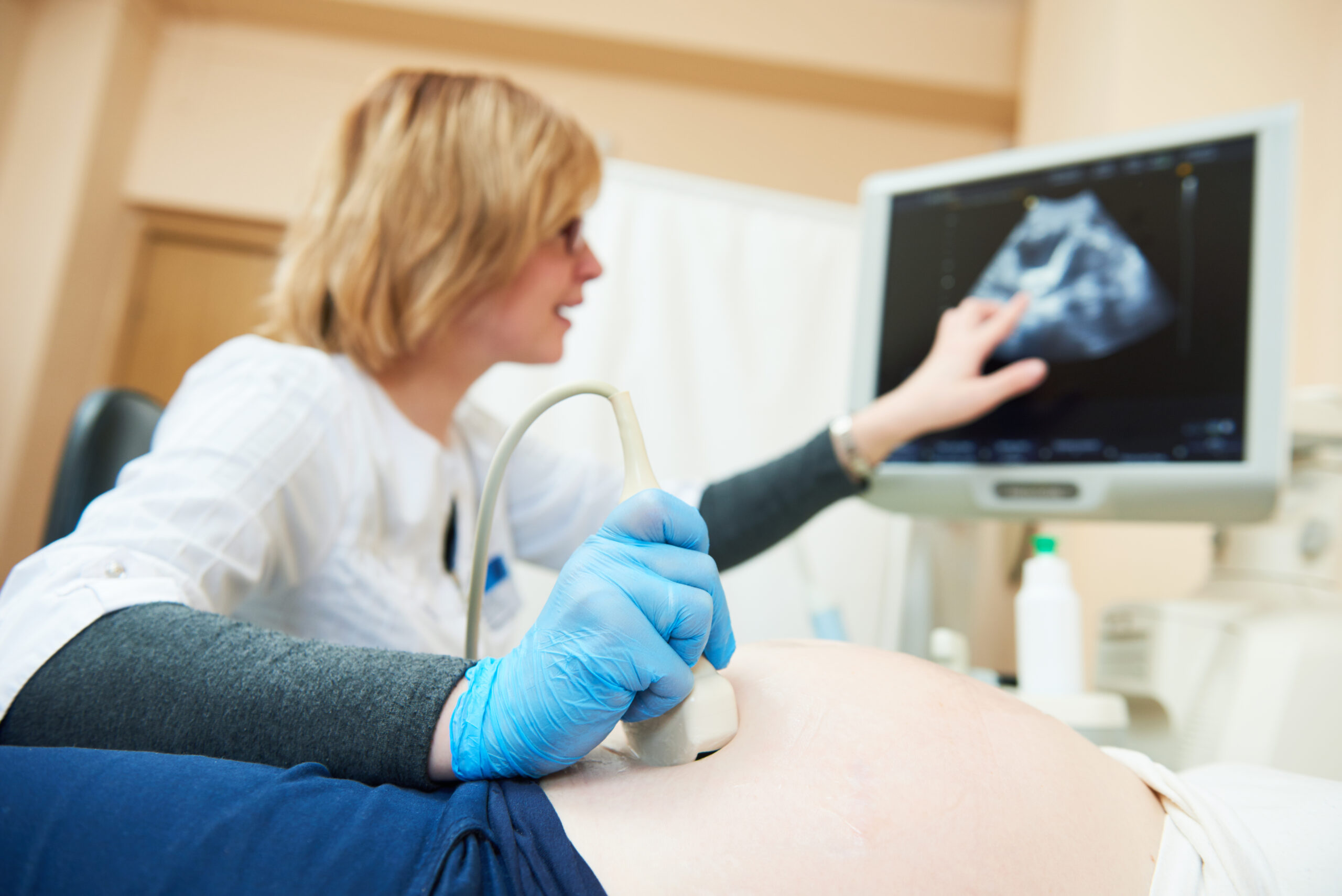 Ultrasound test. Pregnancy. Female gynecologist doctor checking patient's fetal life signs with scanner.