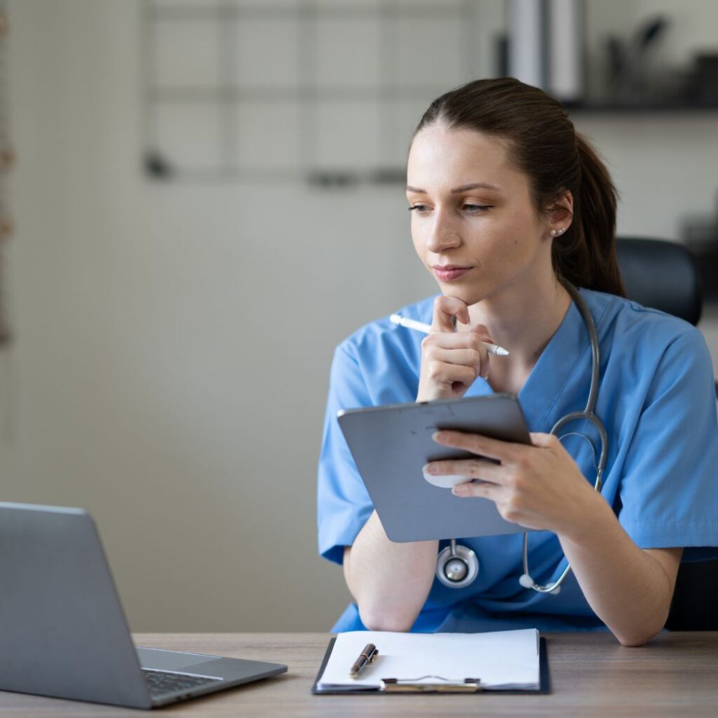 Student looking at laptop with a clipboard and handheld device 